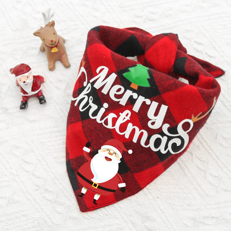 Red and black plaid bandana with "Merry Christmas" text and Santa design. Nearby, Santa and reindeer figurines are placed on a white textured surface.