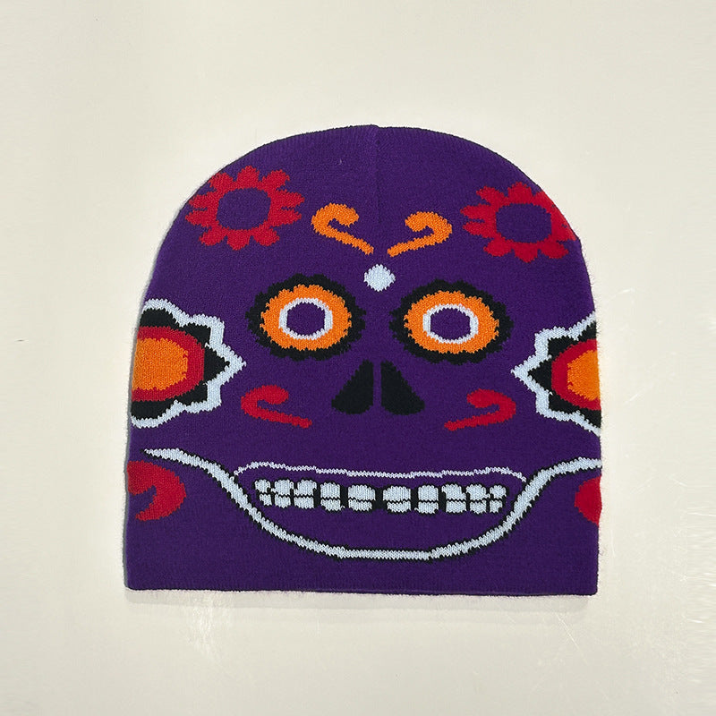 Purple knit beanie featuring a vibrant, colorful sugar skull design with orange and red floral and abstract patterns, inspired by Dia de los Muertos art on a pale background.