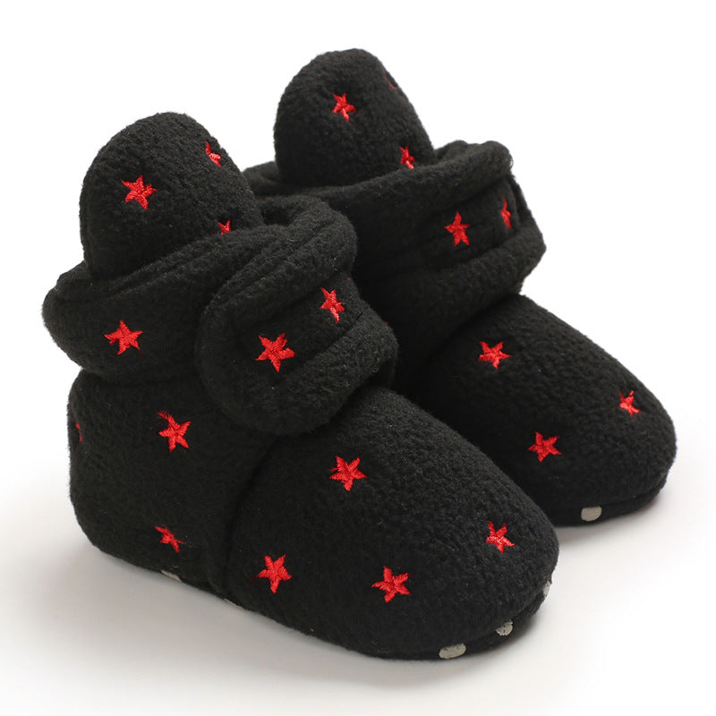 Black fleece slippers adorned with red star embroidery, featuring a cozy, wraparound design and soft soles.