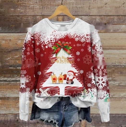 Festive red Christmas sweater with a white tree, Santa, and reindeer design surrounded by snowflakes. Paired with denim shorts, it hangs on a wooden background.