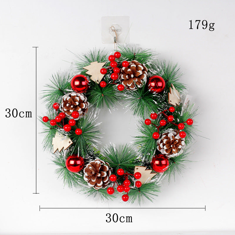 Festive wreath with green foliage, red berries, pine cones, and red baubles, accented with wooden tree shapes. Measures 30cm in diameter and weighs 179g.