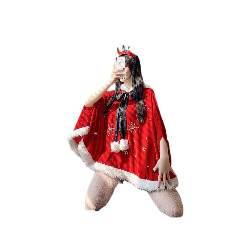 Person taking a selfie, kneeling in a red and white fur-trimmed cape with snowflake designs, wearing a reindeer headband and fishnet stockings.