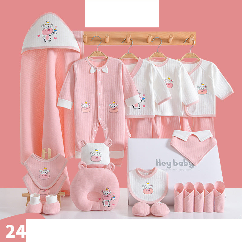 Set of pink and white baby clothes with cow design, including onesies, bibs, hooded towel, mittens, and socks, displayed on a rack against a pink background.