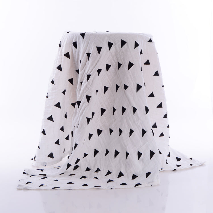 White fabric with a pattern of small black triangles draped over a surface against a light background.