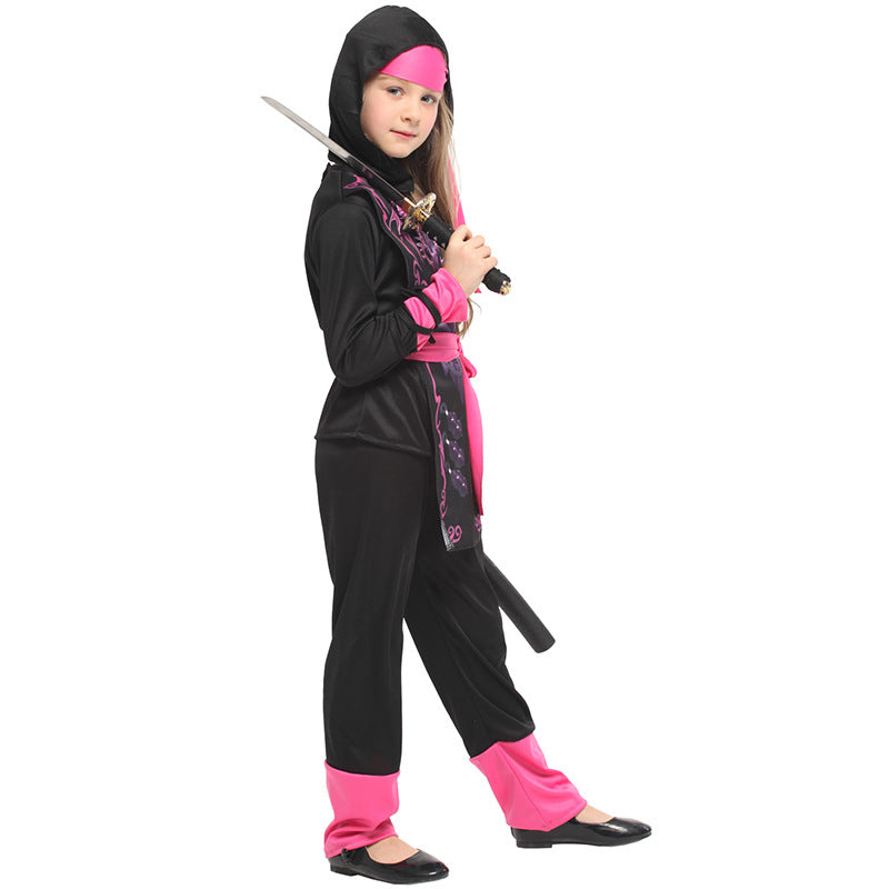 Child dressed as a ninja in a black and pink outfit, holding a sword. The costume features a hood, belt, and pink accents, with a graphic design on the torso.