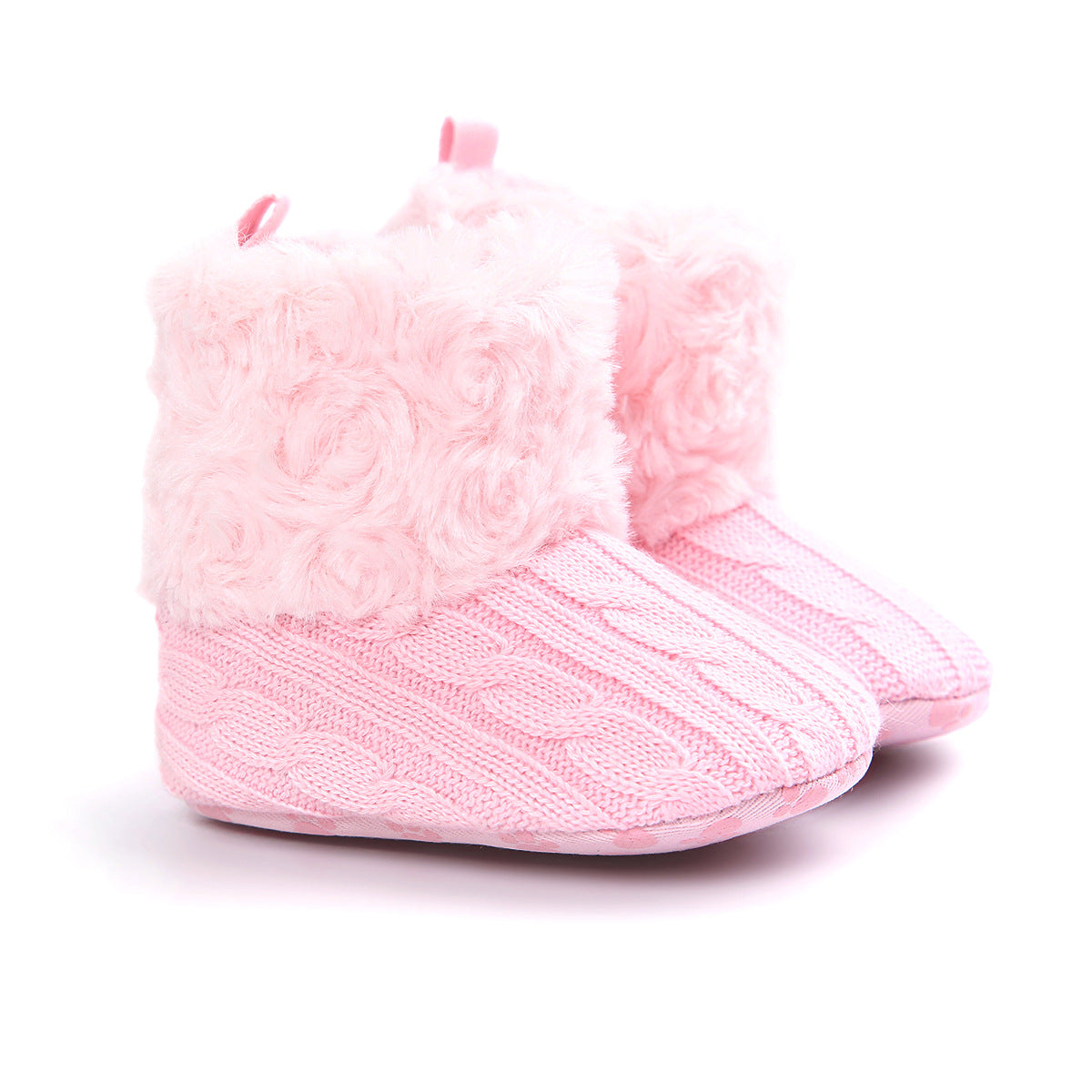 Pink baby booties with a knitted cable pattern and fluffy cuffs. They have a soft texture and a cozy, warm look, suitable for infants.