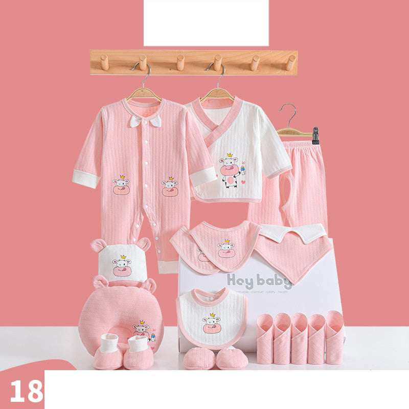 Set of pink and white baby clothes and accessories with cute cow designs, including onesies, pants, bibs, hats, mittens, and a box, all displayed against a pink background.