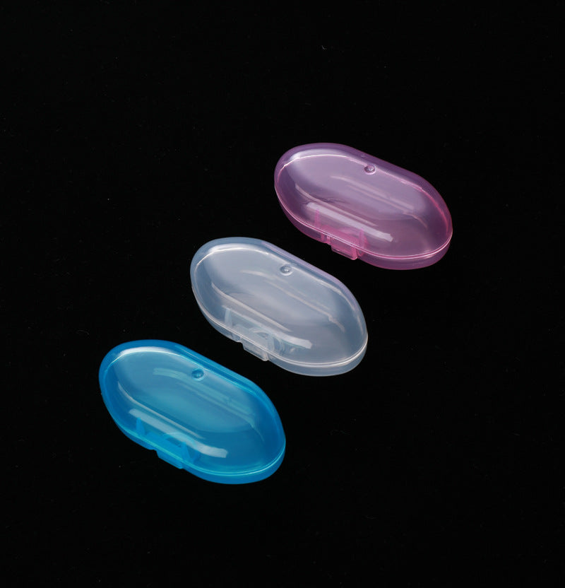 Three oval-shaped, plastic soap holders in pink, clear, and blue on a black background.