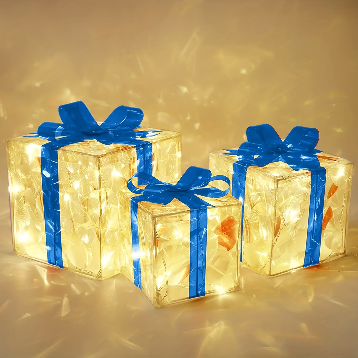 Three illuminated gift boxes with blue ribbons are glowing from within. The transparent boxes emit a warm yellow light, casting reflections on the surrounding surface.