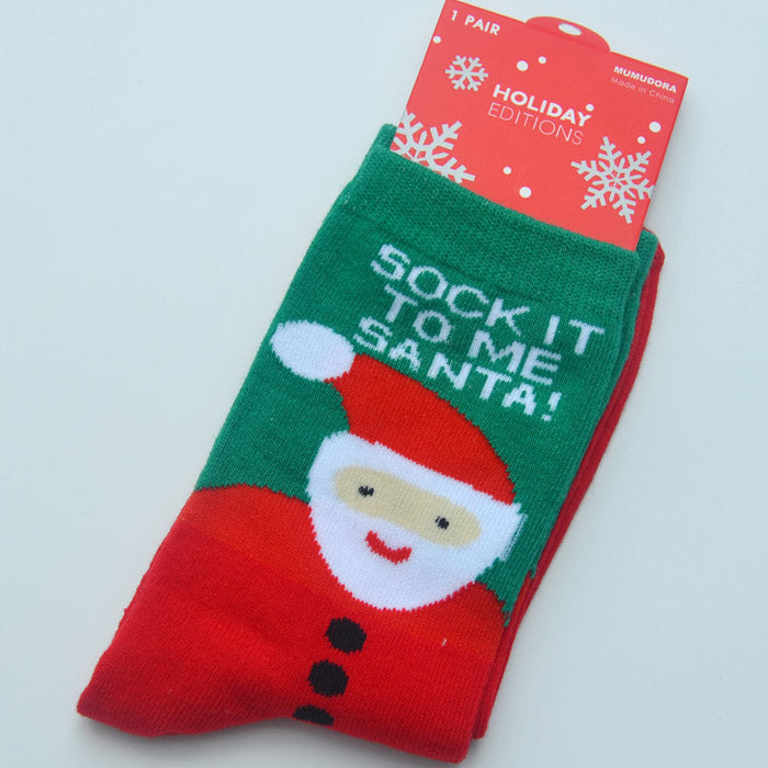 Festive socks with a Santa design and the phrase "Sock it to me Santa!" on a green background. They're packaged with a red holiday-themed card featuring white snowflakes.