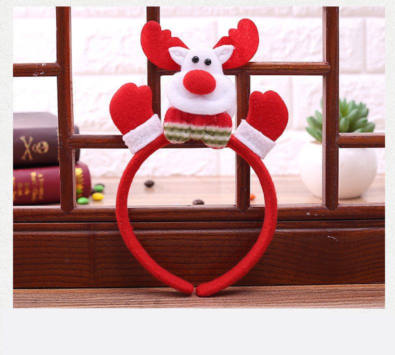 Red and white reindeer headband featuring plush antlers and mittens, with a festive design, displayed against a wooden and brick background.