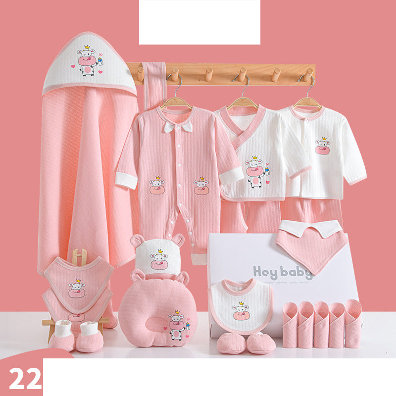 Baby clothing set in pastel pink and white featuring a cute cow design includes a bodysuit, pajamas, bib, socks, towel, mittens and more on a matching pink background.