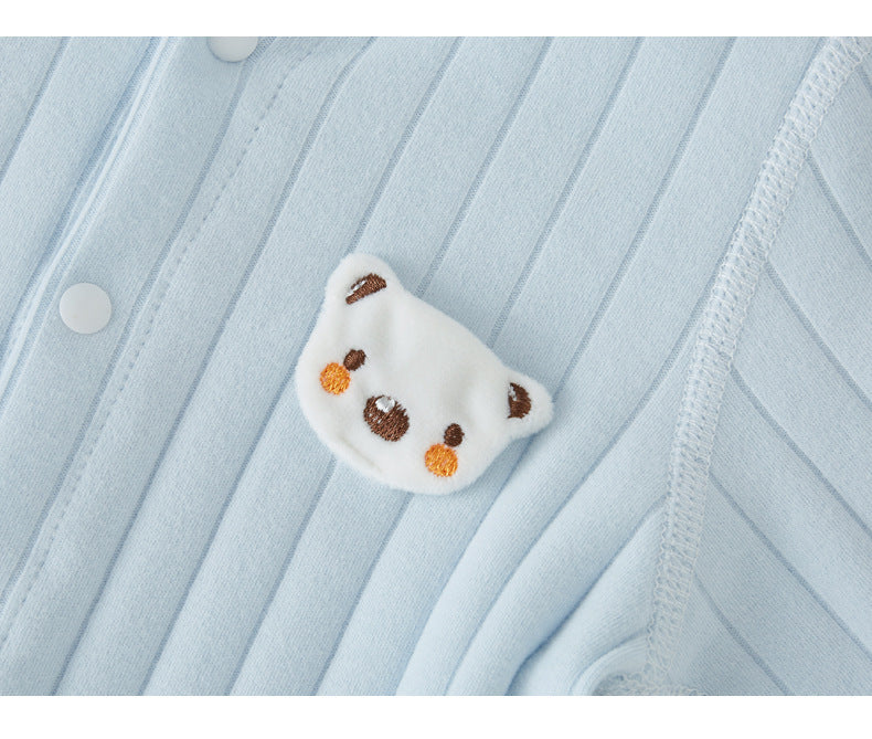 Close-up of a light blue onesie with subtle stripes, featuring a cute embroidered bear face in white with brown ears and nose, and orange cheeks on the left side.