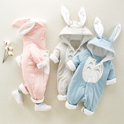 Three infant onesies with bunny ears and Totoro designs in pastel pink, gray, and blue are displayed on a light background with a small sprig of cotton beside them.