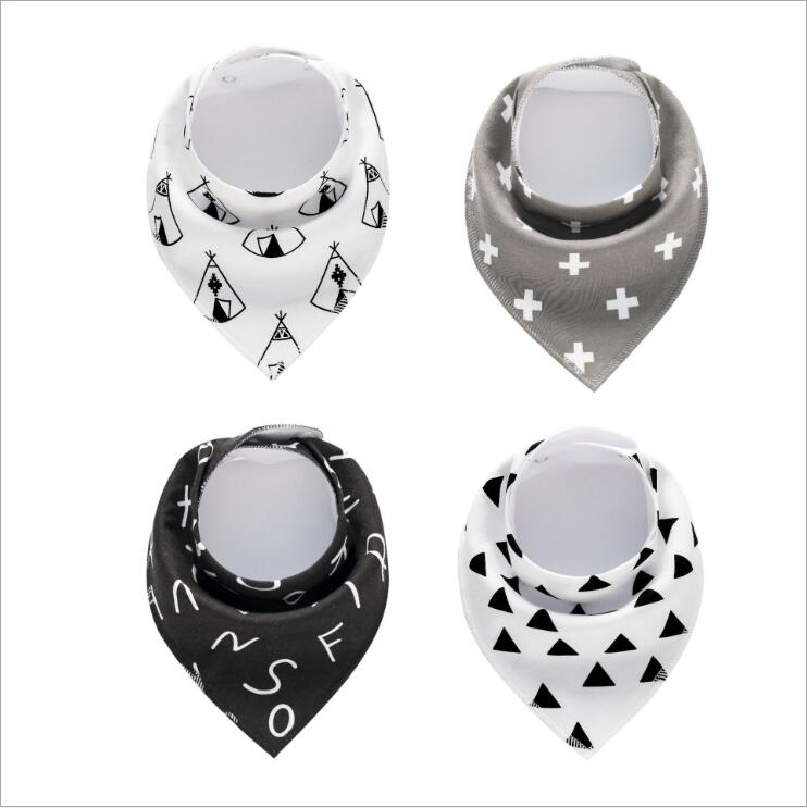 Four baby bandana bibs with geometric patterns: top left features teepees, top right has white crosses on gray, bottom left shows black with white letters, bottom right has black triangles.