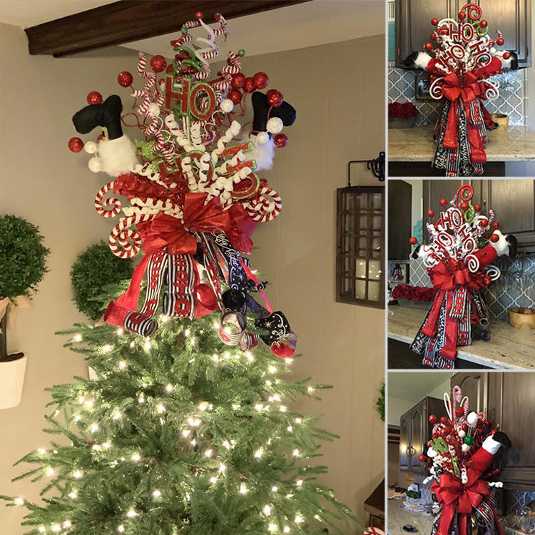 Festive Christmas tree topper with "Ho Ho Ho" sign, red and white spiral ornaments, a large red bow, and decorative ribbons. The tree is adorned with warm white lights.