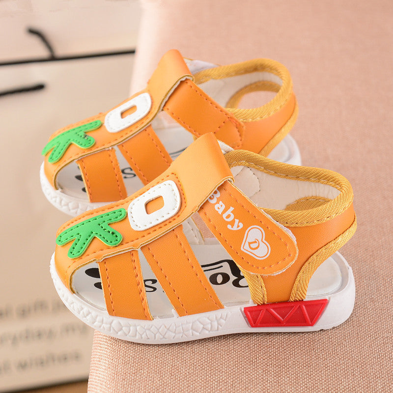 Orange toddler sandals with green leaf and white patch details, open-toed design, and white soles with red accents. The word "baby" is printed on the side strap.