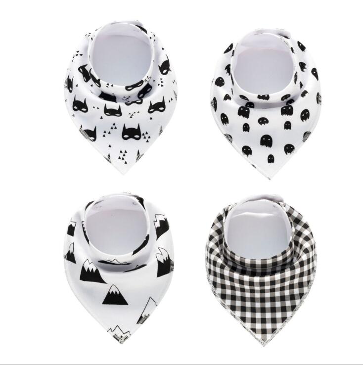 Four baby bandana bibs with different patterns: masks, ghosts, mountains, and checkered design. Each bib is crafted from soft, white fabric featuring black prints.