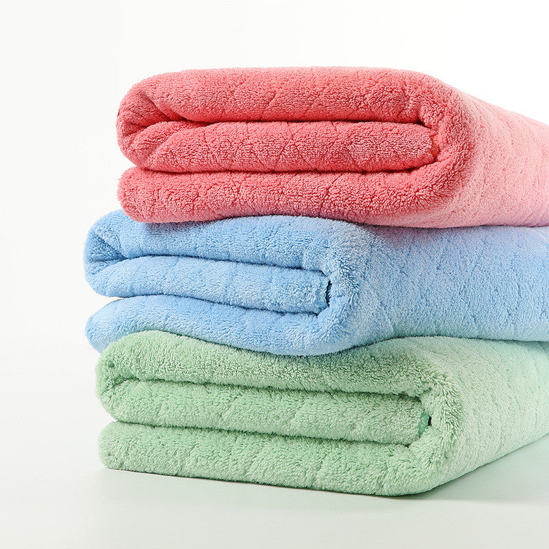 Three neatly folded towels in pastel colors stacked on top of each other: pink on top, blue in the middle, and green on the bottom, against a white background.
