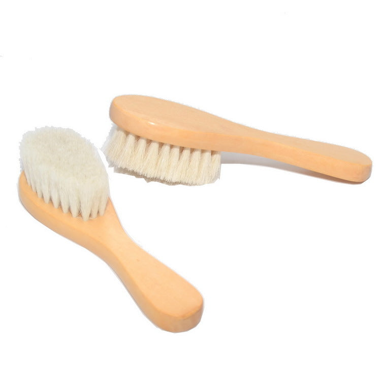 Two wooden brushes with soft, white bristles lying on a white background. The brushes have smooth, light brown handles and are positioned at angles to each other.