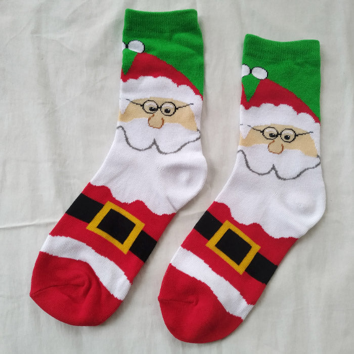 Pair of festive socks with a Santa Claus design, featuring his face, glasses, and classic red and white suit with a black belt. The top is green with white pom-poms.