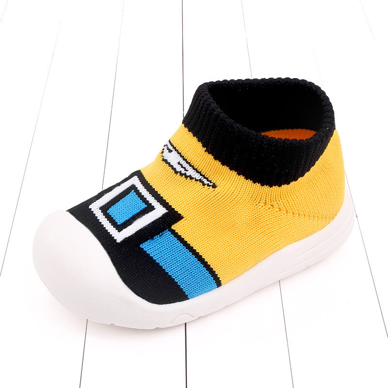 Yellow and black children's slip-on shoe with a white toe and blue geometric design on a white wooden floor background.
