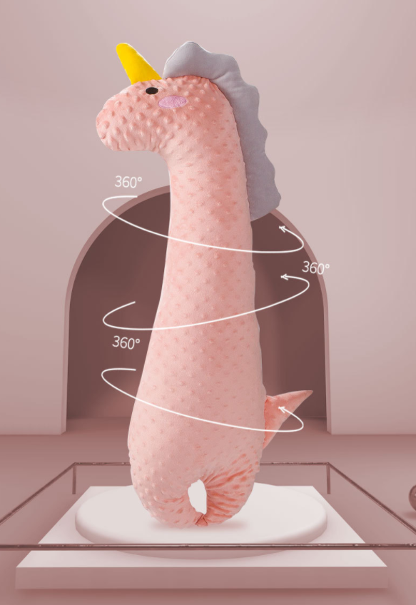 Plush pink dinosaur with a yellow horn and gray mane stands on display. Arrows encircle it with "360°" labels, against a soft pink, arched background.