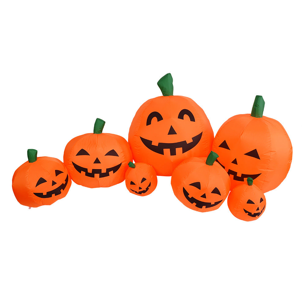 Inflatable pumpkin decorations with smiling faces, varying in size, are grouped together. Each orange pumpkin has a green stem on top, creating a festive Halloween display.