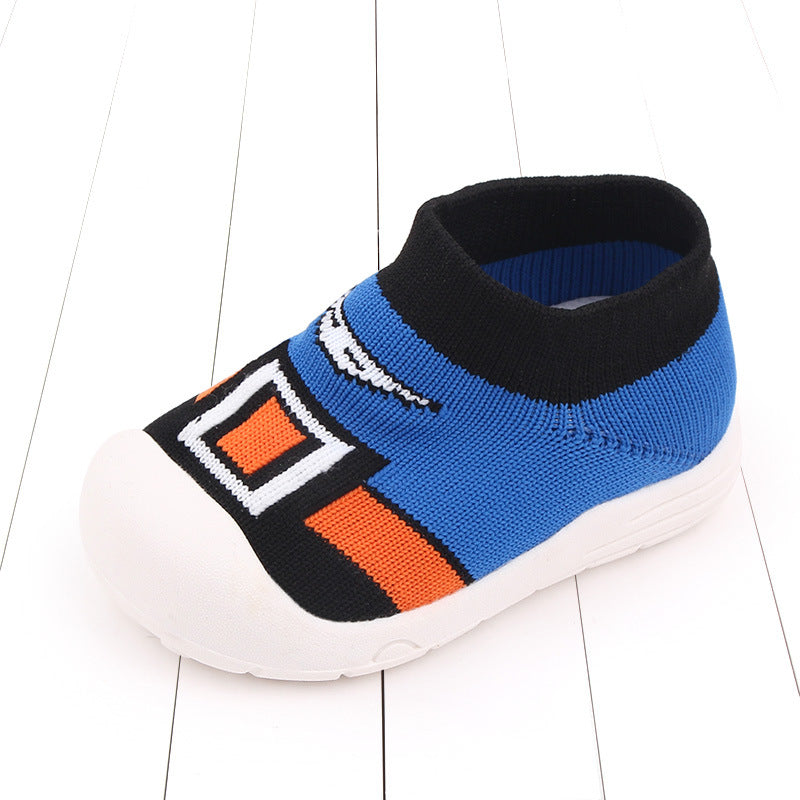 Toddler shoe with a soft knit upper in blue, black, and orange geometric design. It features a rounded white rubber sole, black collar, and a slip-on style on a white background.