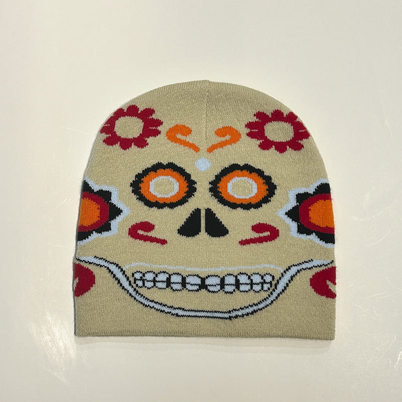 Beanie hat featuring a colorful Day of the Dead skull design, with floral patterns, vibrant orange and red accents, and a broad toothy grin on a beige background.