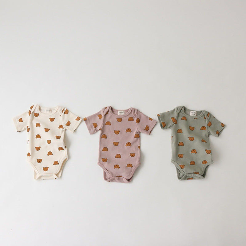 Three baby onesies on a white background, featuring bear patterns. The onesies are in off-white, mauve, and sage green colors.