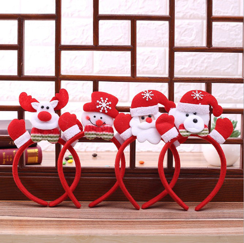 Four festive headbands with plush designs: a reindeer, snowman, Santa, and a polar bear, all wearing red Santa hats with snowflakes, are displayed on a wooden surface.