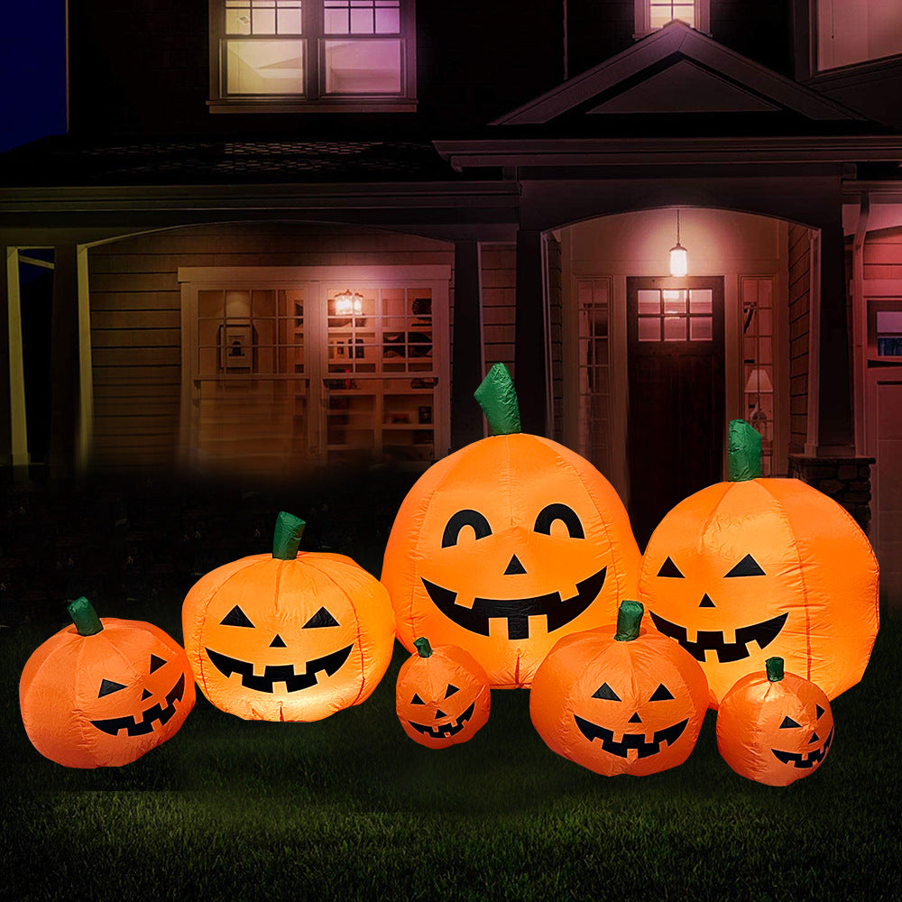 Inflatable Jack-o'-lanterns of various sizes with smiling faces are illuminated and displayed on the lawn of a house at night, creating a festive Halloween atmosphere.
