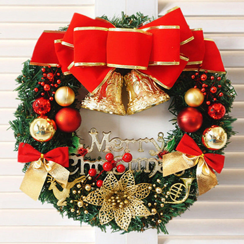 Festive Christmas wreath adorned with red and gold ornaments, large bows, golden bells, and metallic "Merry Christmas" text, against a white wooden background.