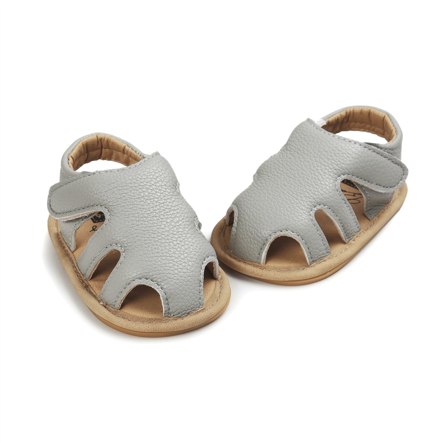 Gray leather baby sandals with a textured finish, featuring cutouts and a soft brown sole. The sandals have a velcro closure for easy fastening, suitable for infants.