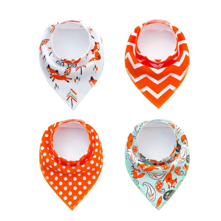 Four baby bibs are displayed: one with foxes, one with orange chevrons, one with white polka dots, and one with foxes and mushrooms on a light teal background.