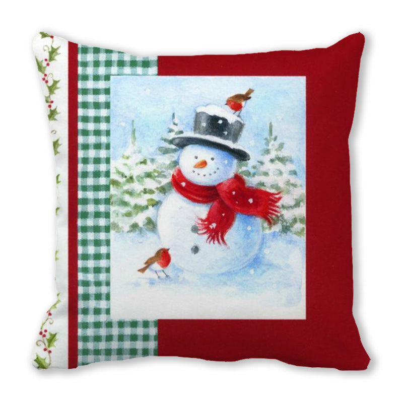 Festive cushion with a snowman wearing a top hat and red scarf, surrounded by robins. The background features snowy trees, red borders, and green checkered patterns.