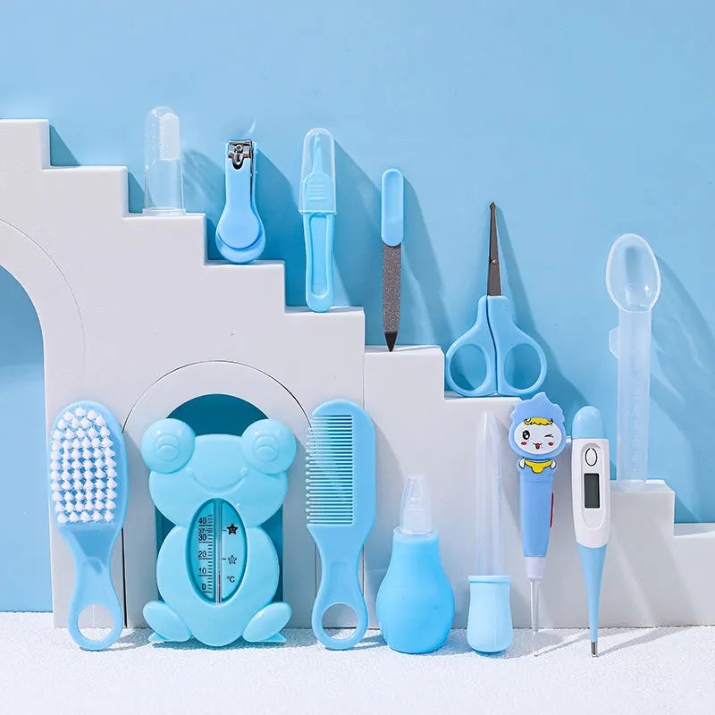 A collection of baby care items in blue, including a thermometer, nail clipper, scissors, comb, brush, nasal aspirator, and toothbrush, arranged on a white stepped platform.