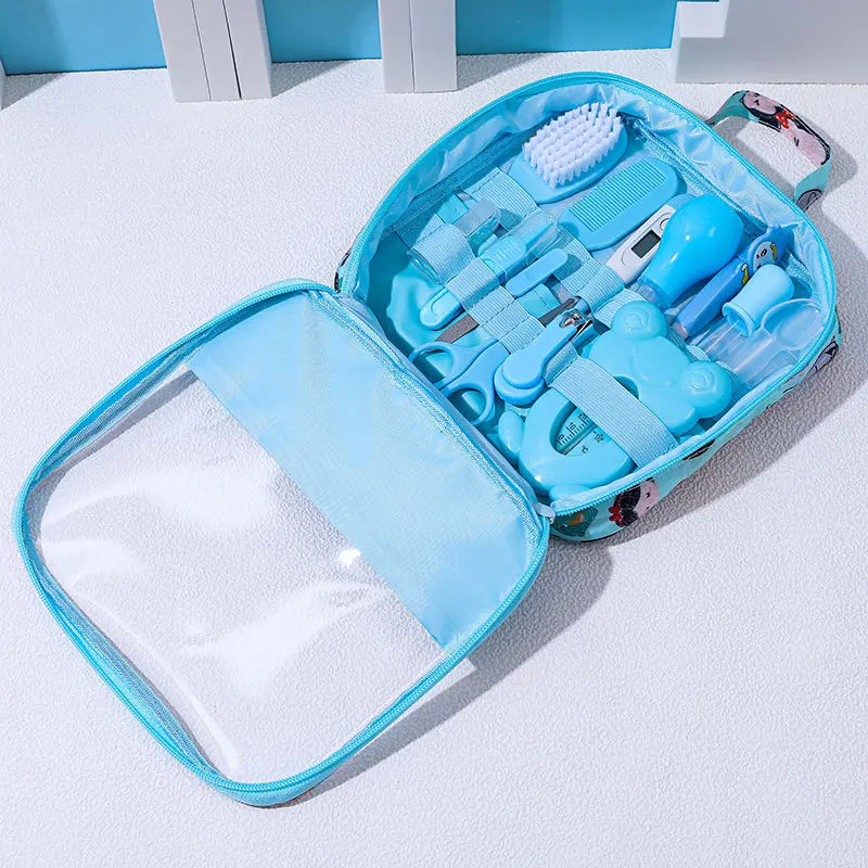 Open baby grooming kit in a light blue case on a white surface, containing nail clippers, scissors, a thermometer, brush, comb, and other baby care items.