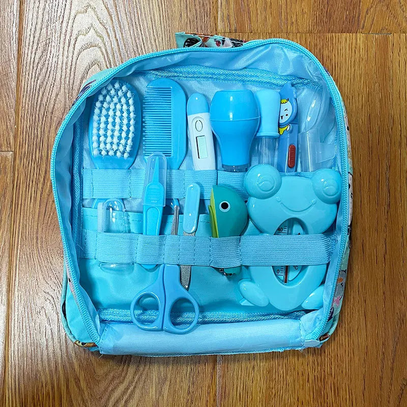 Blue fabric pouch containing a set of baby grooming tools, including a brush, comb, thermometer, nail clippers, scissors, and droppers, all neatly organized for easy access.