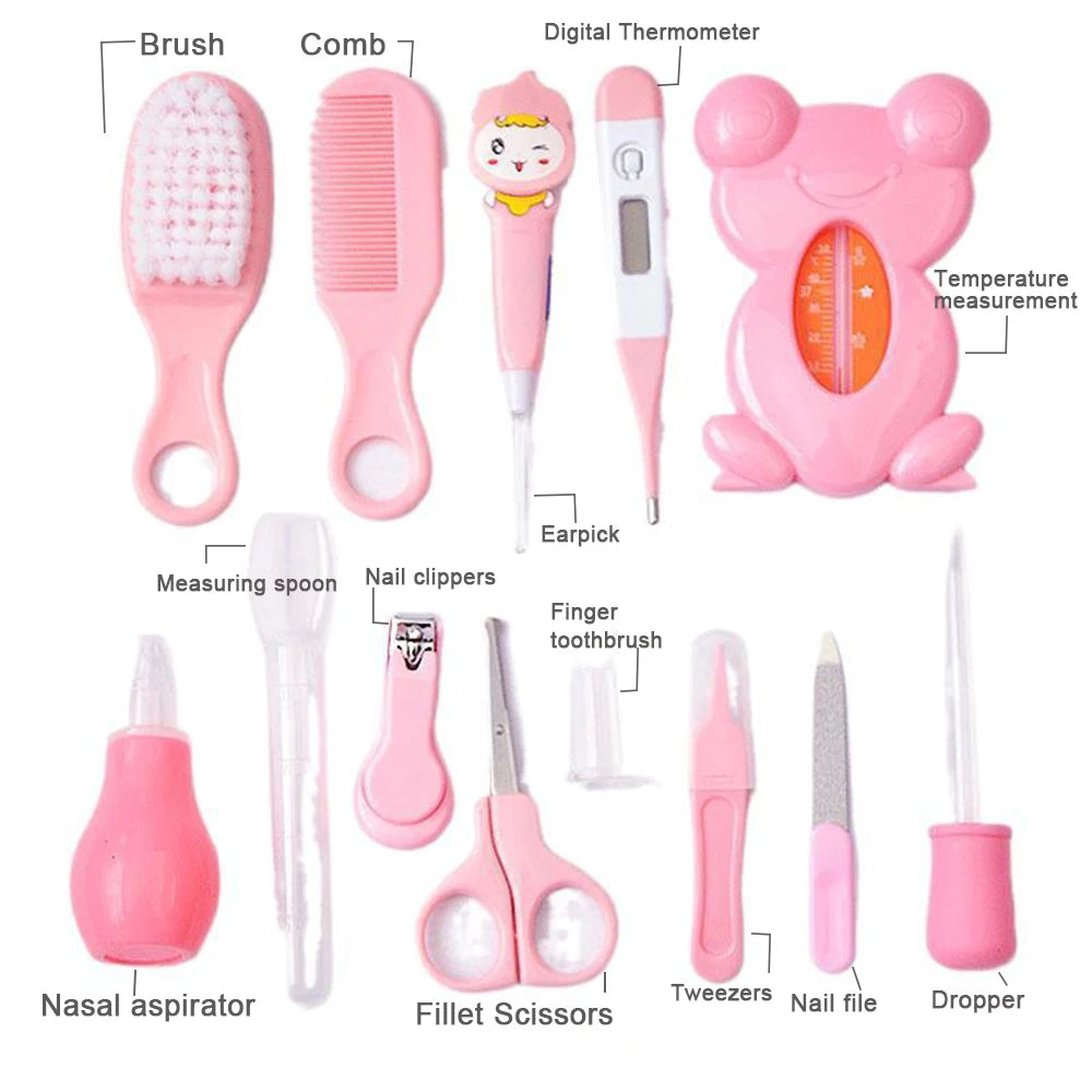 Baby grooming kit in pink with labeled tools: brush, comb, digital thermometer, ear pick, temperature measurer, nasal aspirator, spoon, clippers, scissors, toothbrush, tweezers, nail file, dropper.