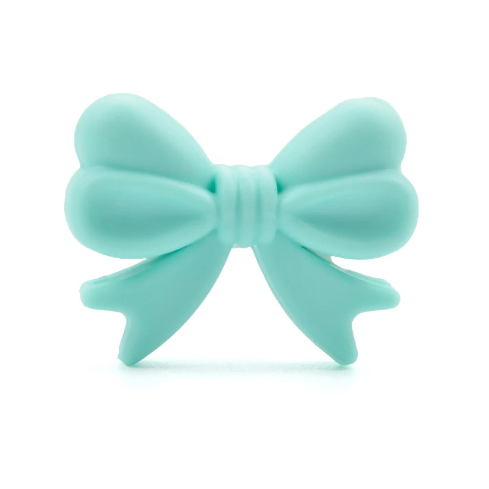 A mint green bow-shaped object with rounded loops and neatly tied center. The bow's soft texture suggests it's made of rubber or silicone.