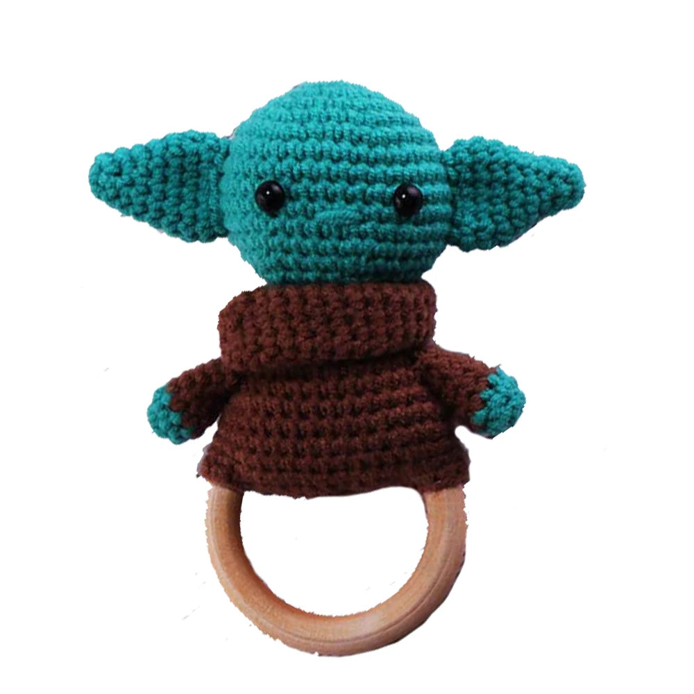 Crocheted green alien figure with large ears, wearing a brown robe, attached to a wooden ring.