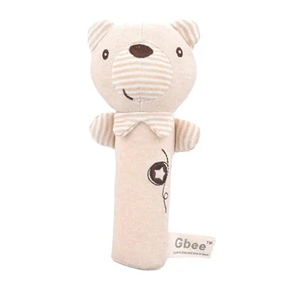 Soft beige teddy bear rattle with embroidered eyes, a stitched smile, and a striped neck section. It features a small label with "Gbee" on the side.