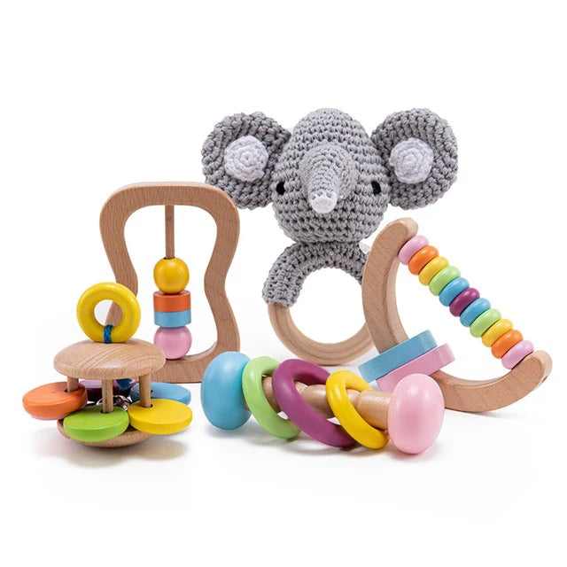 Colorful baby toys including a crocheted elephant rattle, a wooden bead maze, and curved bars with multicolored rings. Made from wood and yarn, perfect for sensory play.