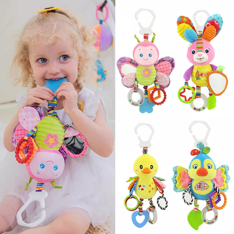 A child in a white dress chews on a colorful, plush butterfly toy. Four additional plush animal toys, each with rings and clips, are displayed to the right.