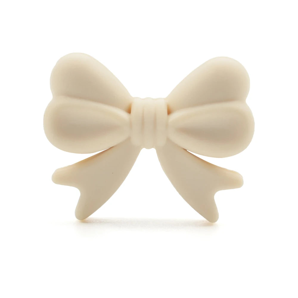 Cream-colored bow with rounded loops and pointed tails, resembling a heart shape on both loops. The bow is centered and distinctly separated against a white background.
