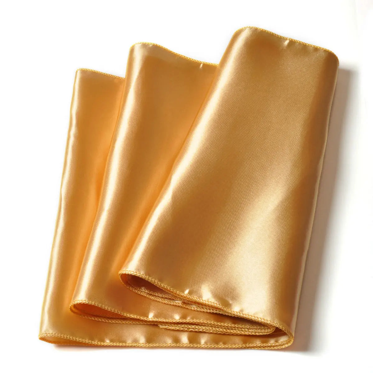Folded shiny golden satin fabric with a smooth texture and neatly stitched edges on a white background.