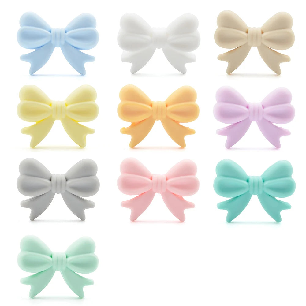 Colorful set of ten bow-shaped figures in pastel shades: blue, white, beige, yellow, orange, lilac, grey, pink, mint green, and turquoise, arranged in a grid pattern.