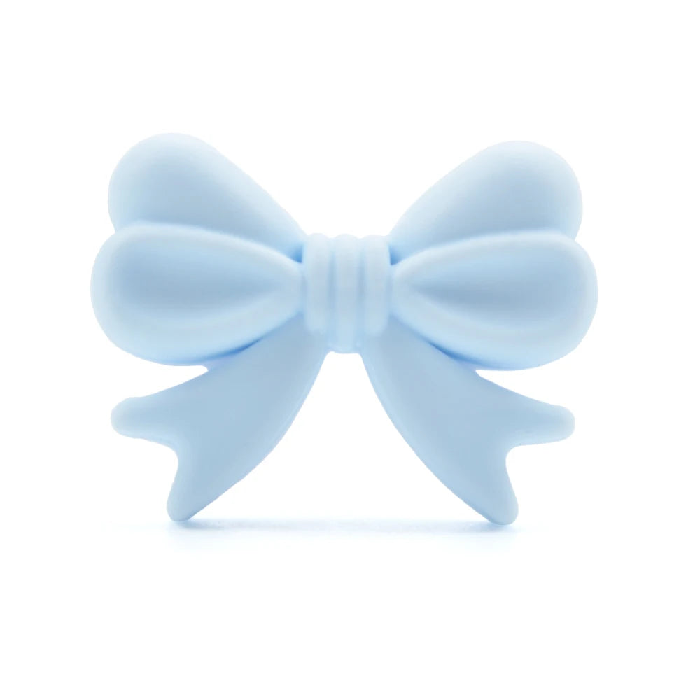 A soft blue silicone bow with textured loops and tails, shown against a white background. The design is simple and resembles a decorative ribbon knot.